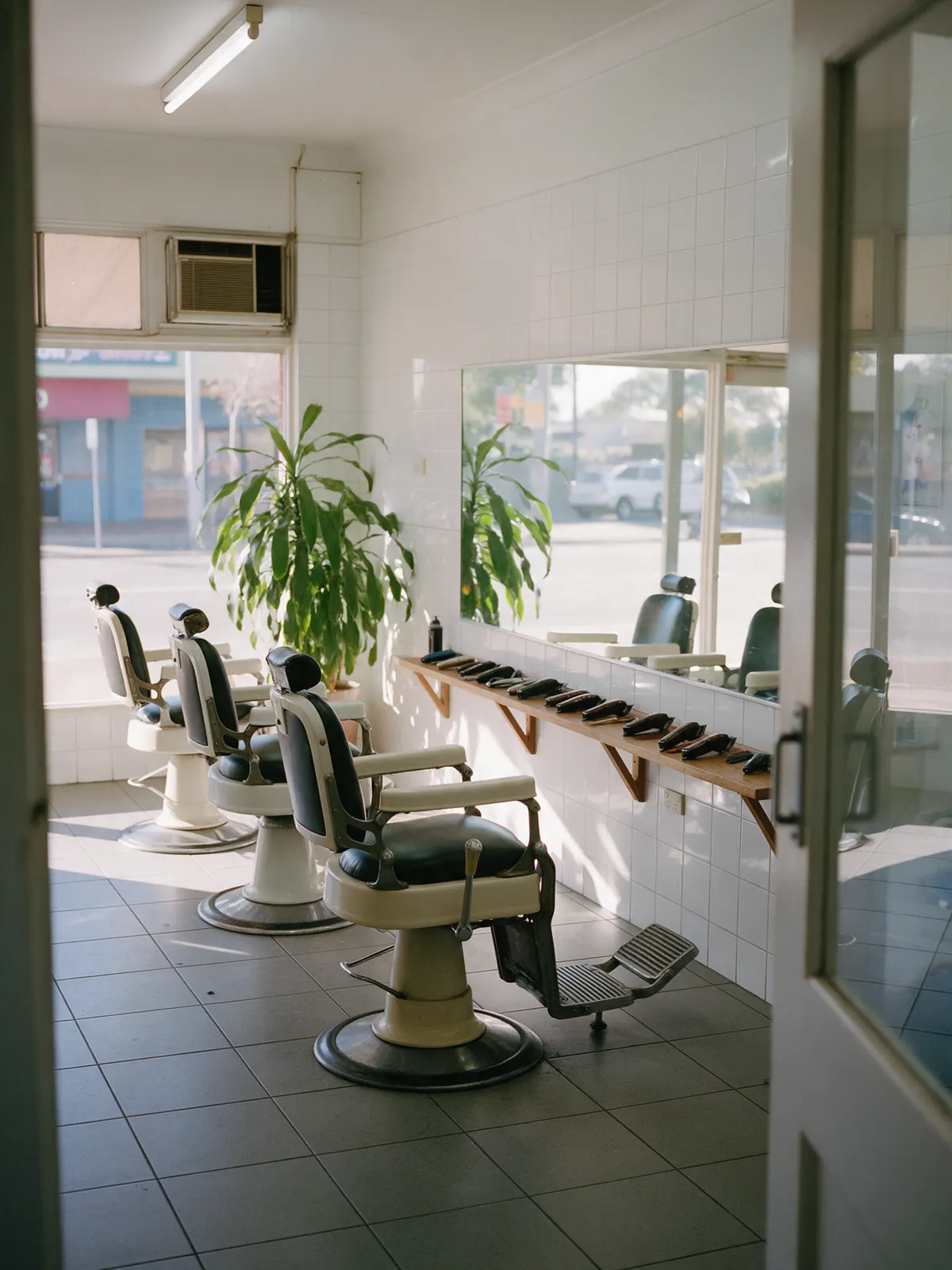Inside the shop: three barber chairs facing the mirrors in morning light